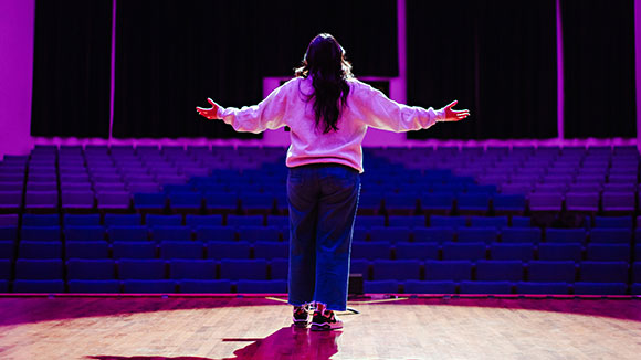 Student performing vocal on stage with back facing the camera.