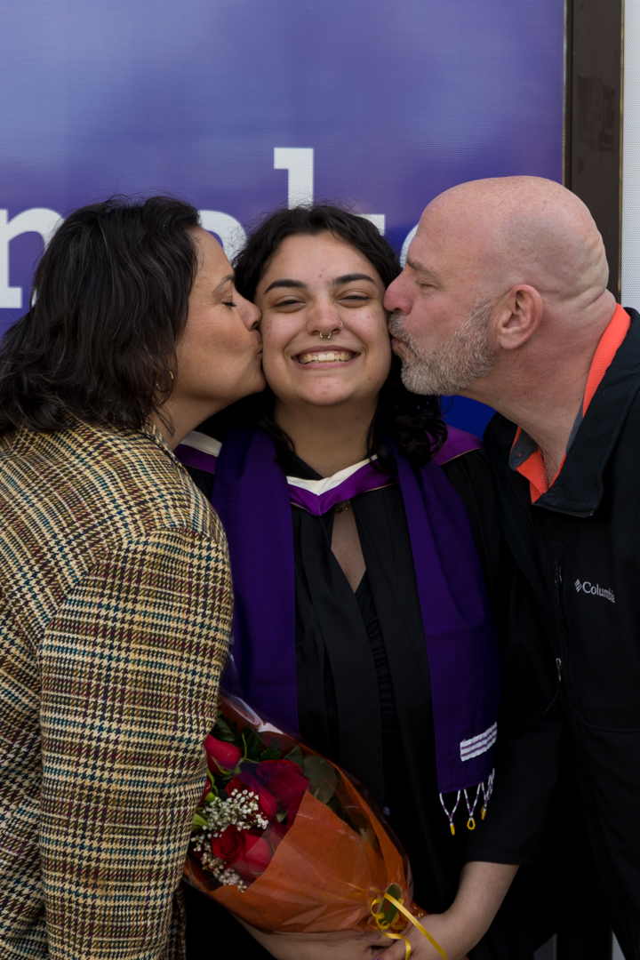 family kisses graduate's cheek